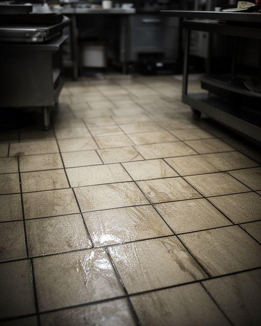 Commercial prep area tile with grease film and darkened grout before thorough cleaning
